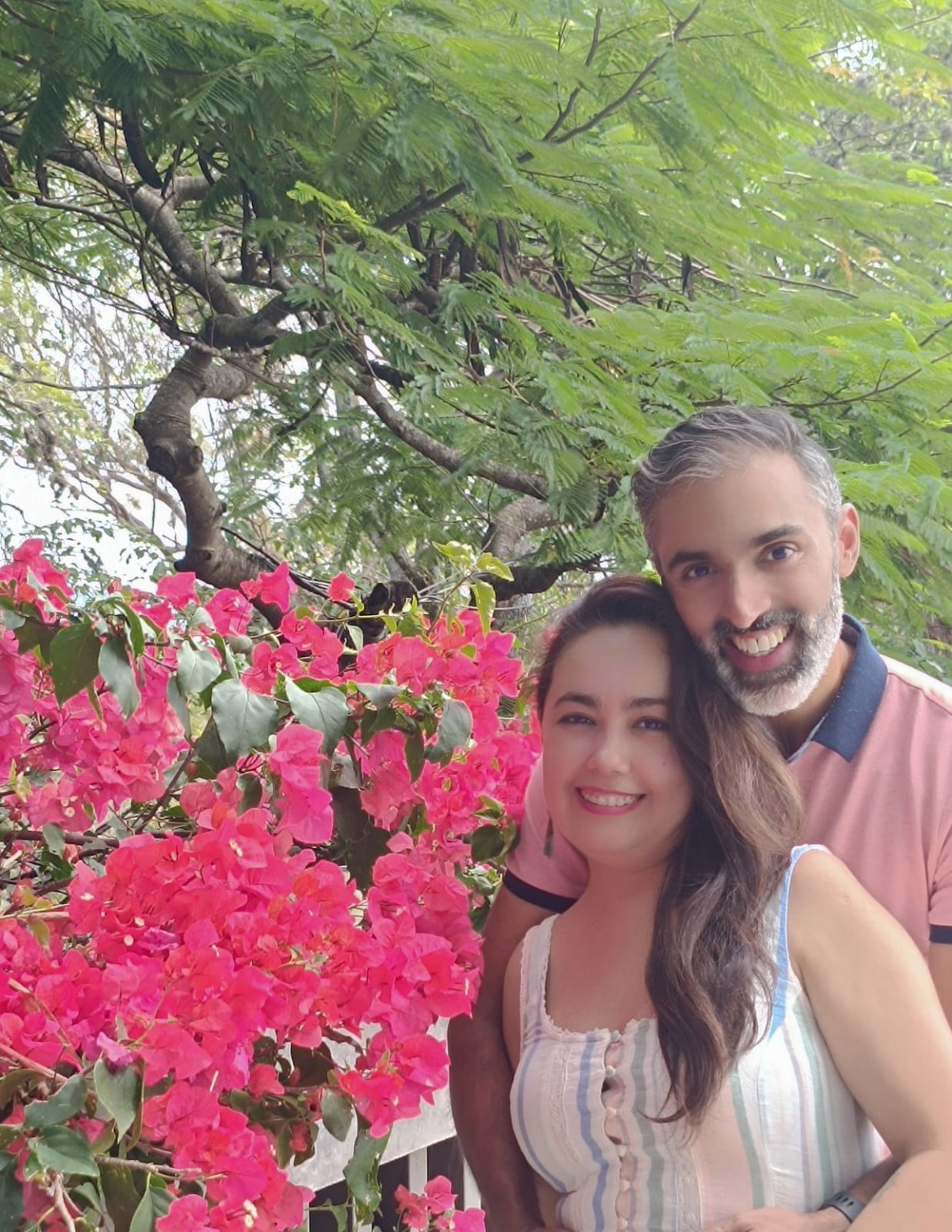 La pareja sonriendo entre flores rosas